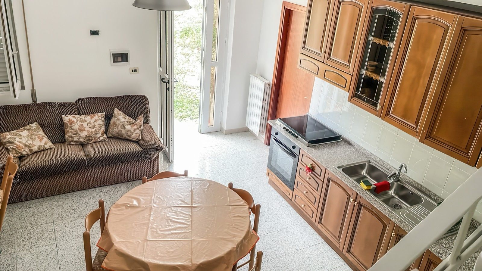 Una cucina con mobili in legno, forno a incasso e lavello.