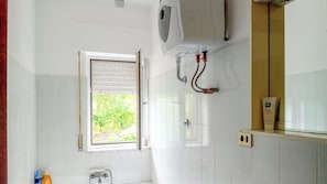 Ein Badezimmer mit Fenster, Warmwasserbereiter und Handtuchspender.