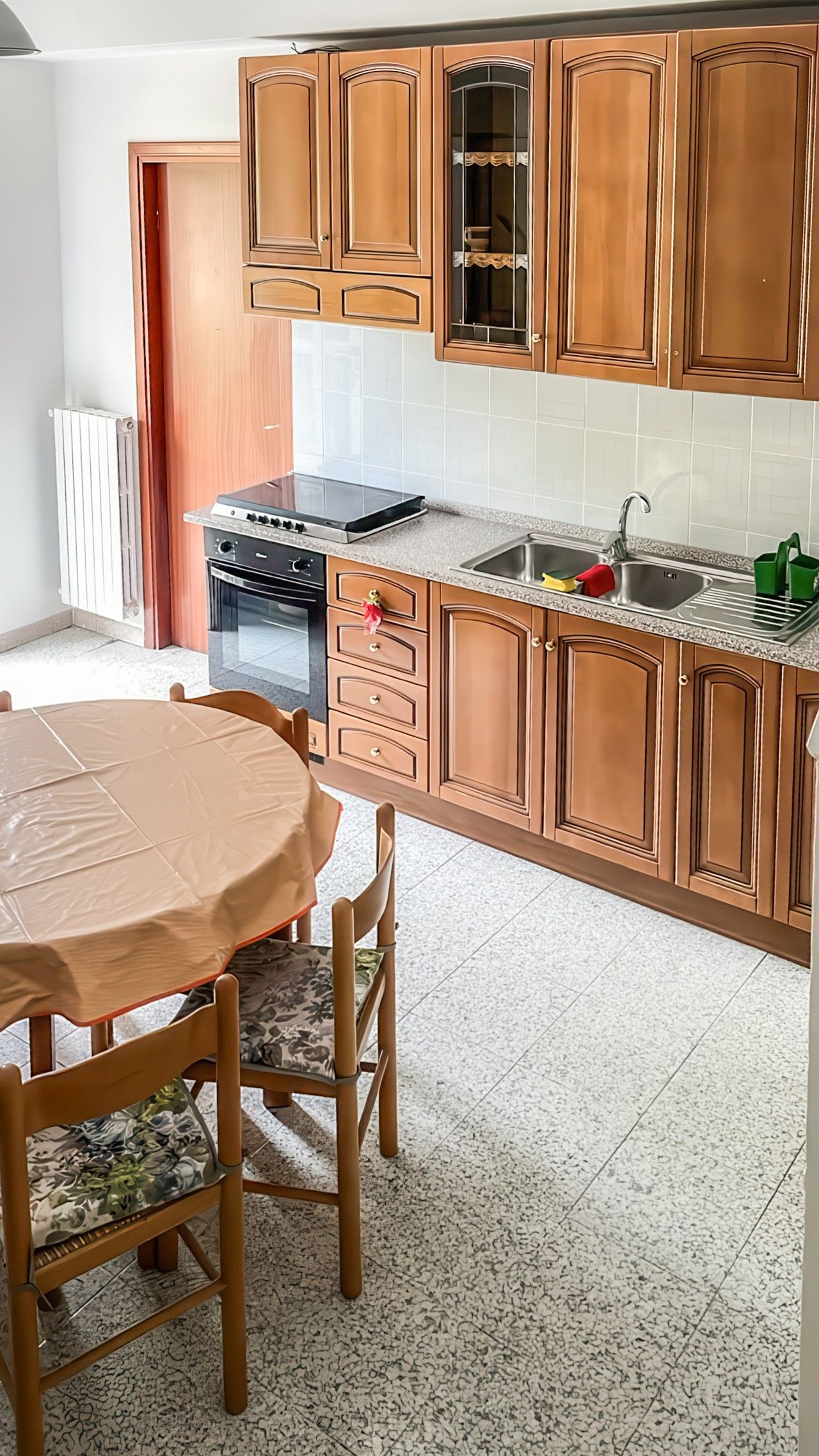 Una cucina con mobili in legno, un piano cottura e un tavolo da pranzo con sedie.