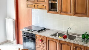 Cuina amb armaris de fusta, fogó i taula de dinar amb cadires.