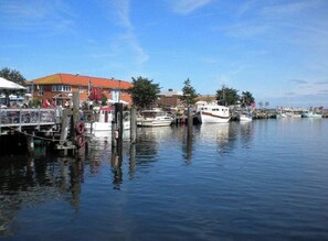 A marina with boats docked, a building with a red roof, and a clear blue sky. - Holiday Apartment With 2 Bedrooms (Heiligenhafen)