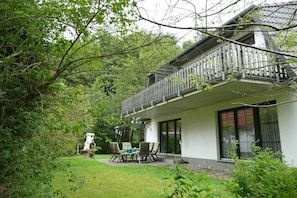 Ein Haus mit Balkon, Rasen und einem weißen Hund.