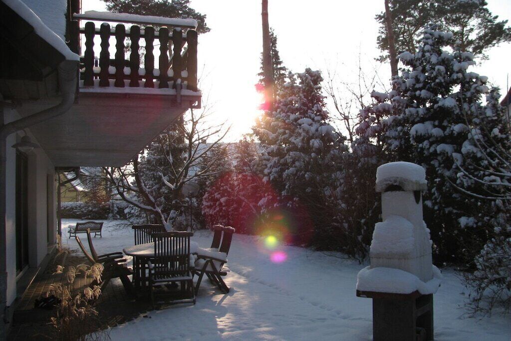 A snow-covered outdoor area with a wooden bench and a snowman.