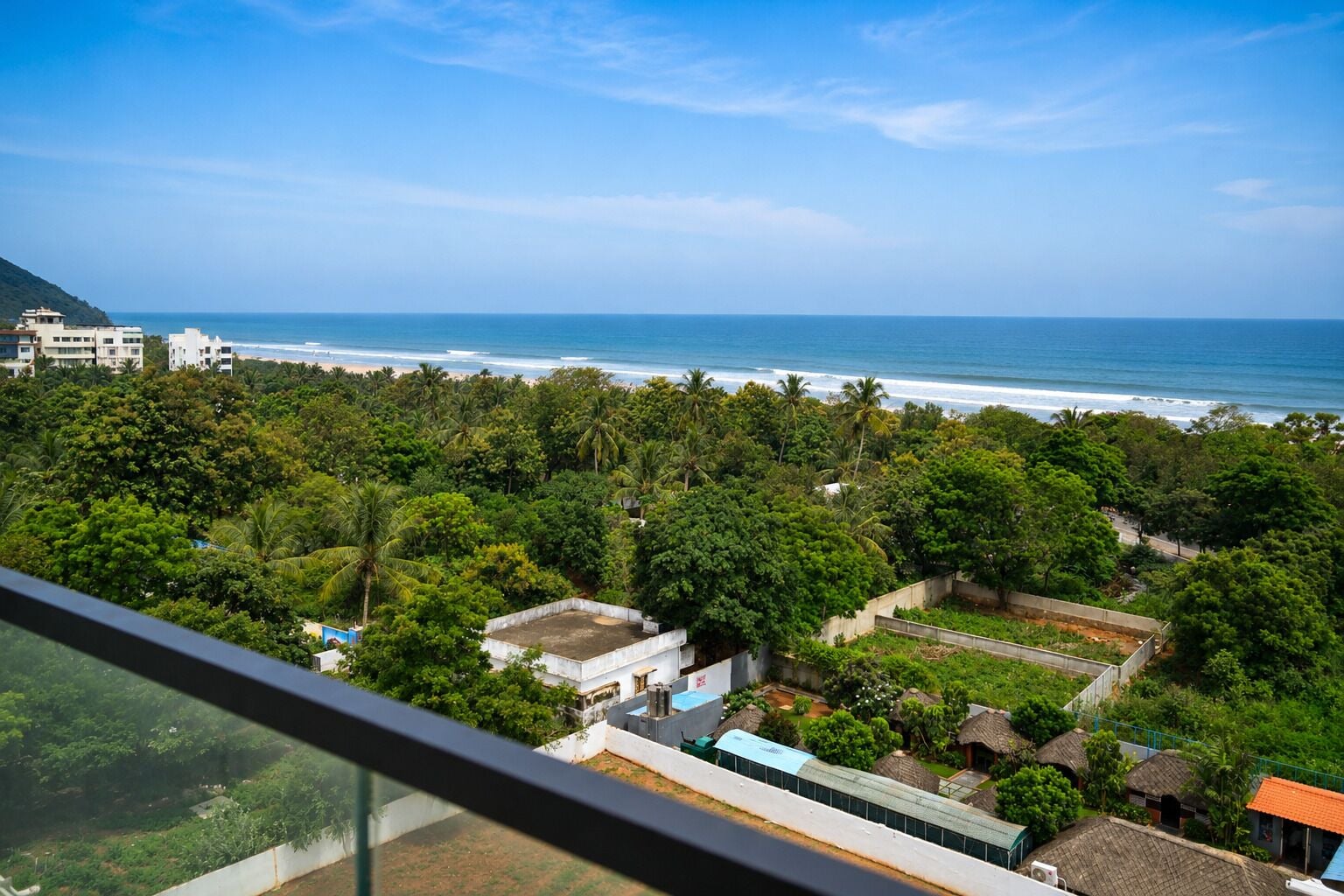 Vista costera con abundante vegetación y una playa a lo lejos.