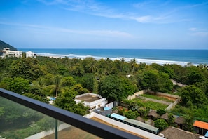 Vista costera con abundante vegetación y una playa a lo lejos.