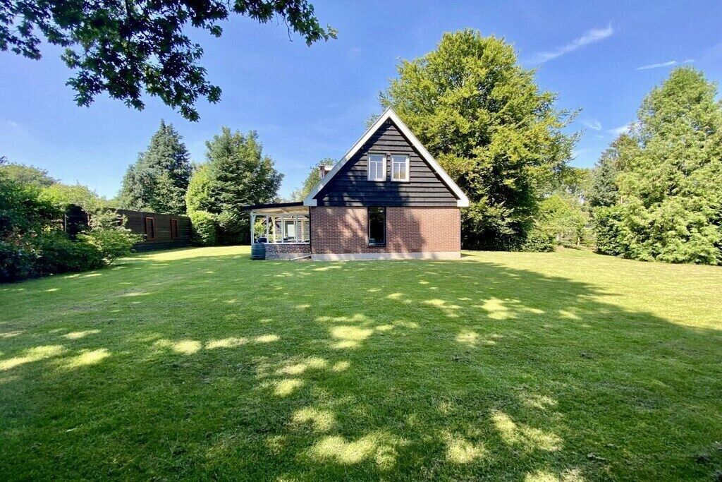 A house with a brick exterior and a gabled roof, surrounded by a well-maintained lawn and trees.