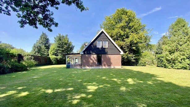 A house with a brick exterior and a gabled roof, surrounded by a well-maintained lawn and trees. - Holiday home in Wapse with swimming pool (Wapse)