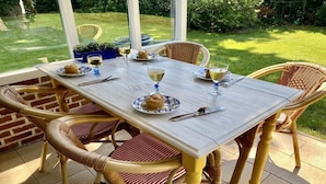An outdoor dining area with wicker chairs and a wooden table set for a meal. - Holiday home in Wapse with swimming pool (Wapse)