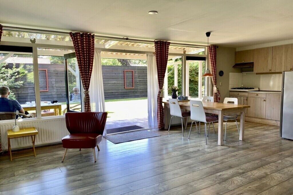 Una cocina moderna con armarios de madera, un comedor con mesa y sillas, y una silla roja.