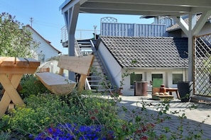 Un patio con un banco de madera, una escalera y un techo de tejas.