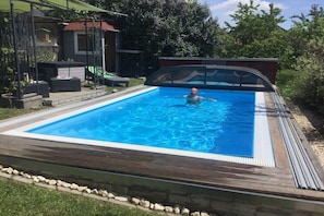 Una piscina rectangular con una terraza de madera alrededor.