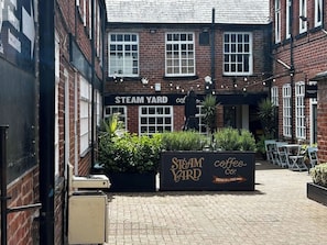 A brick building with a sign reading 'Steam Yard Coffee Co.' and a sign indicating 'Drink in Take Away.'