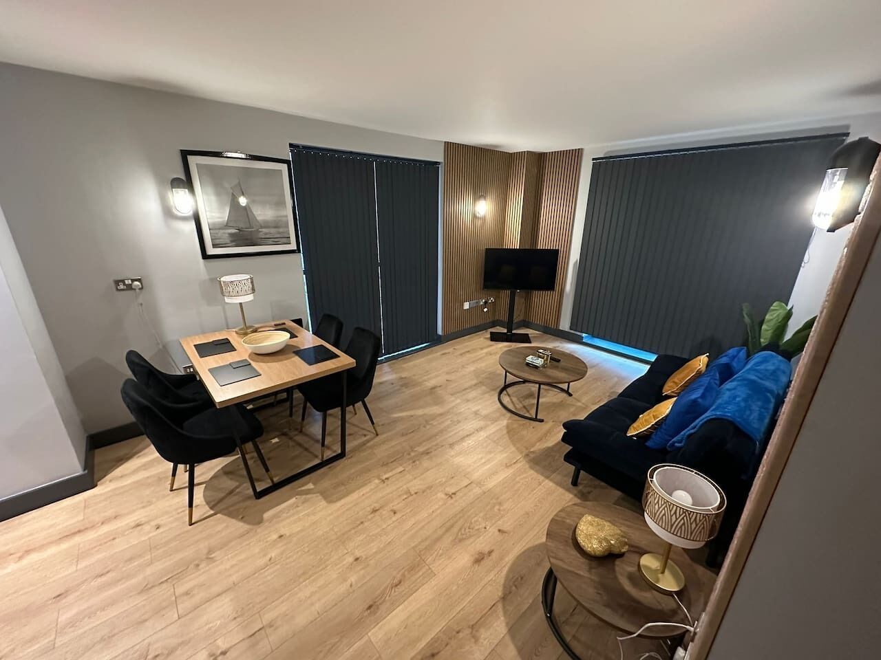 A modern living room with a dining area, a sofa, a TV, and a lamp.