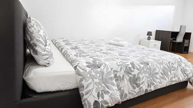 Une chambre à coucher moderne avec un lit, une table de chevet, un bureau et une chaise.