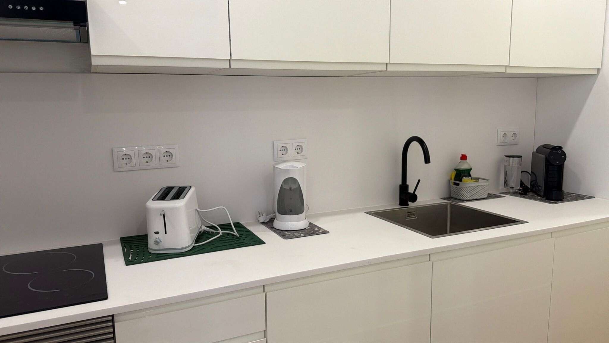 Eine moderne Küche mit Einbauherd, Kaffeemaschine, Toaster, Wasserkocher und Spüle.