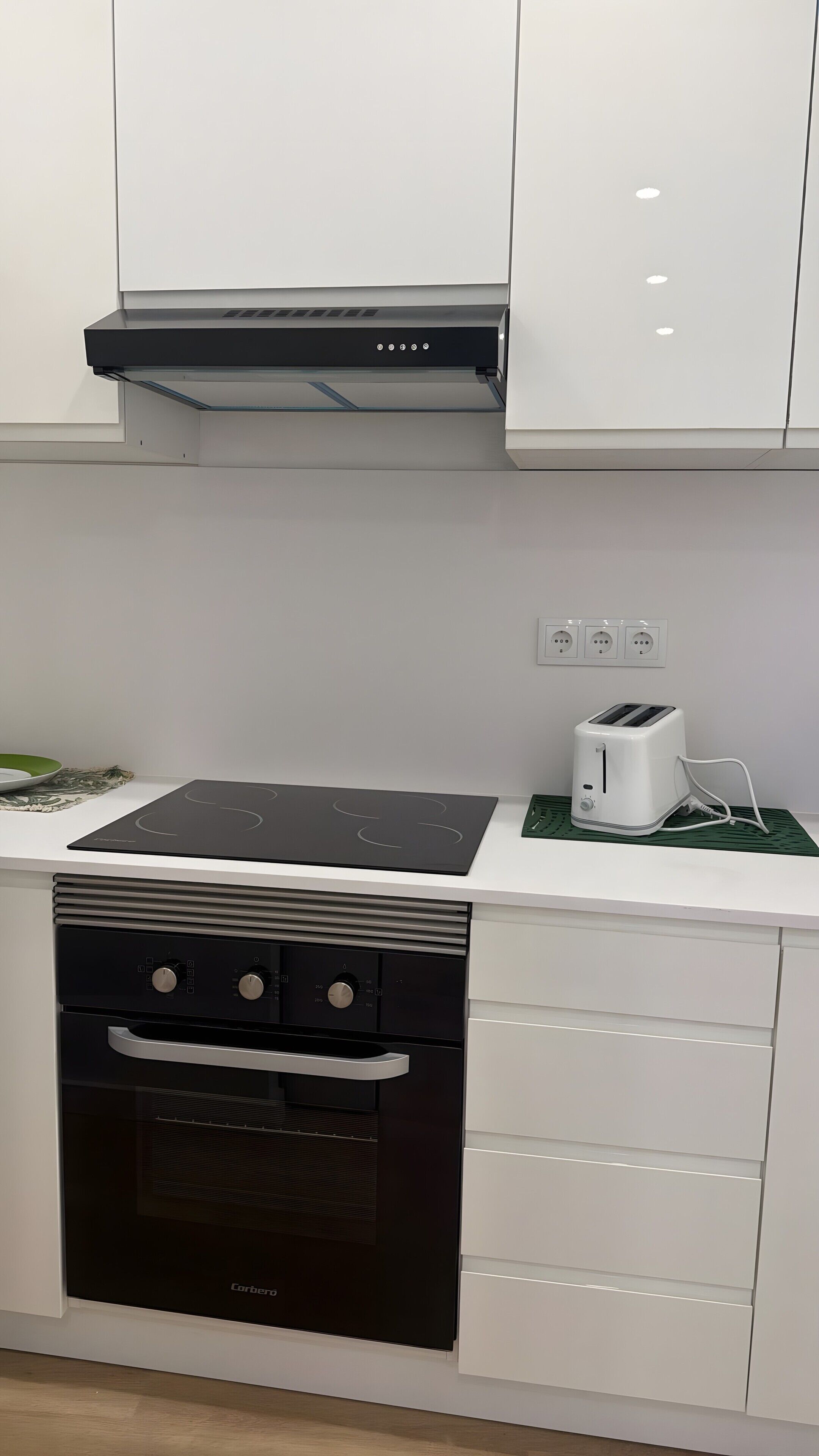 A modern kitchen with a black stove, white cabinets, and a built-in oven.