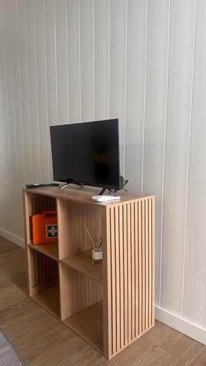 A wooden TV stand with a flat-screen TV and remote control.