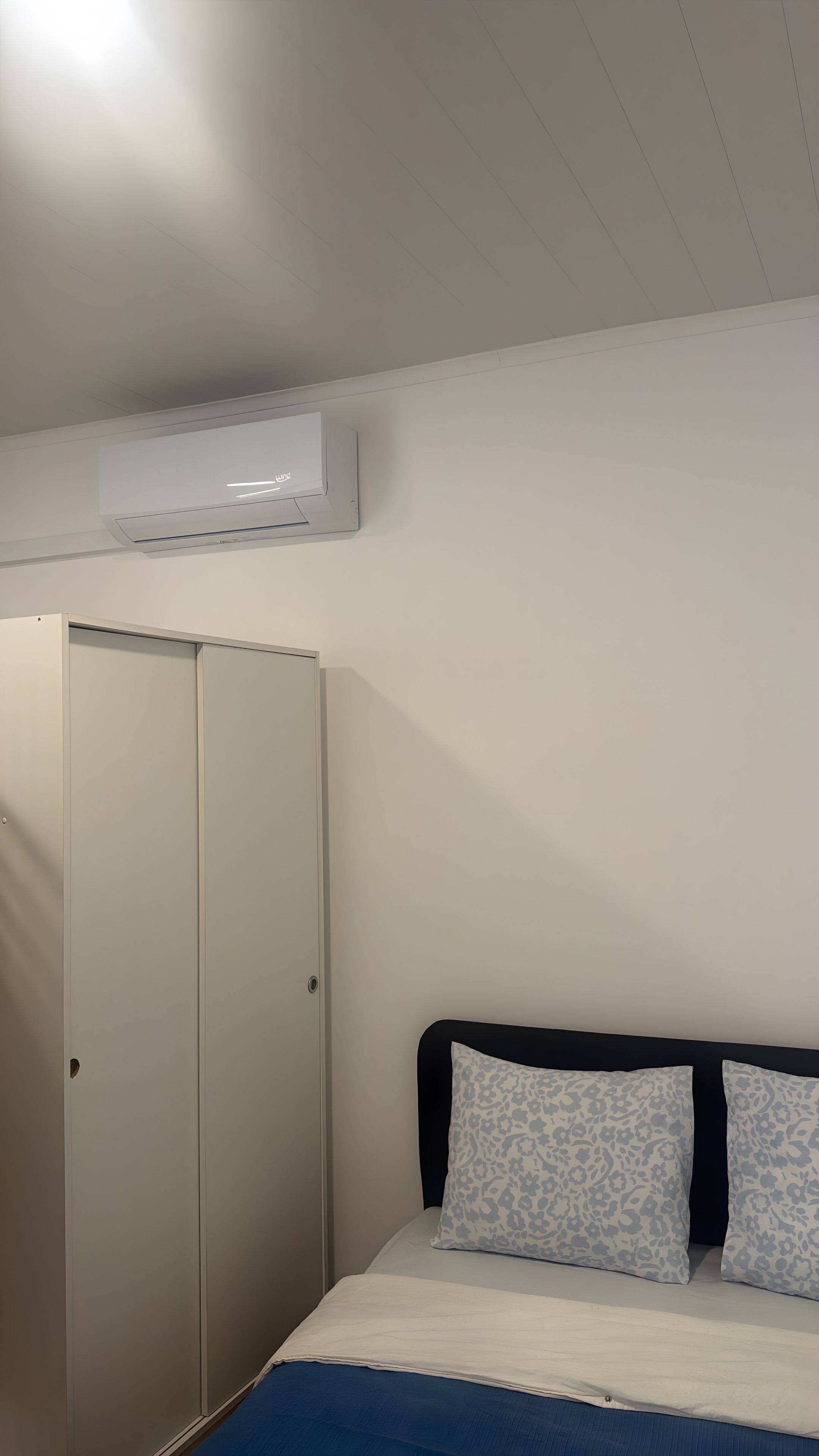 Ein Schlafzimmer mit Bett, Kleiderschrank und Klimaanlage.