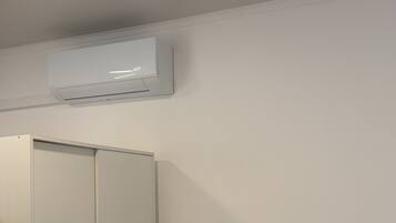 A bedroom with a bed, a wardrobe, and an air conditioning unit.