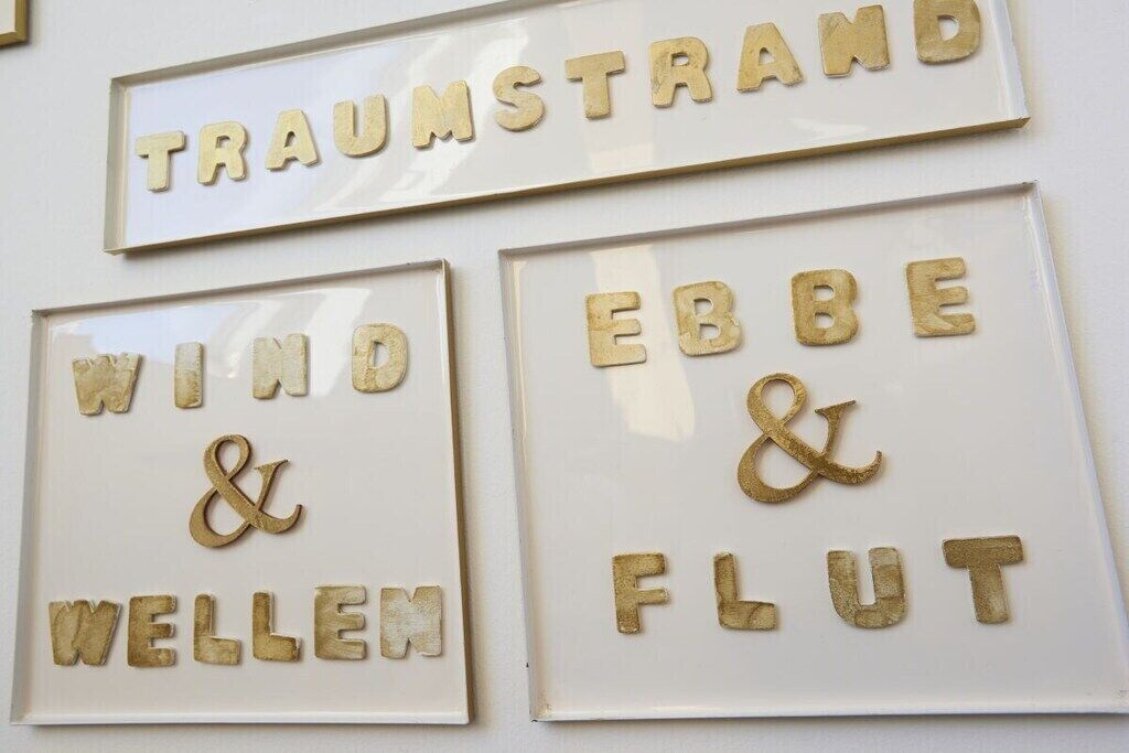 Drei gerahmte Schilder mit Text, vermutlich zur Kennzeichnung von Zimmern oder Themen.