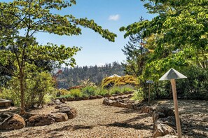 A landscaped garden with a gravel path, rocks, and trees.