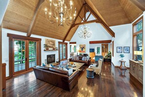 A spacious living area with a high ceiling, wooden beams, a fireplace, and a large seating arrangement.