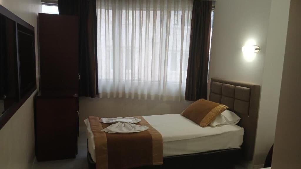 Una camera d'albergo con un letto, un armadio e una finestra con tende.