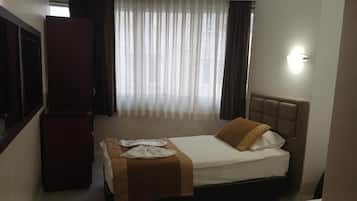 Une chambre d’hôtel avec un lit, une armoire et une fenêtre avec des rideaux.