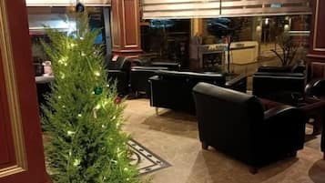 Un hall d’hôtel décoré d’un sapin de Noël, avec des canapés en cuir et une grande fenêtre.