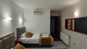 Ein Hotelzimmer mit einem Bett, einem Nachttisch, einem Sessel, einem Spiegel und einem Heizkörper.