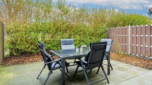 An outdoor patio with a glass-top table and four chairs. - ||---------------------------Crab in Dornum-----------------------|| (Dornum)