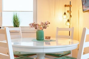 Ein runder Esstisch mit einer grünen Blumenvase, einer Namenskarte und einer kleinen Karte darauf.