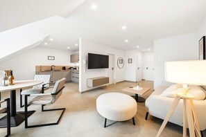 Ett modernt vardagsrum med en matplats, en soffa, ett soffbord och en tv som är monterad på väggen.