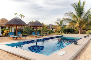 A swimming pool with lounge chairs and thatched-roof structures. - Spacious Villa, 2-Min Beach Walk - AC, Wifi (Pwani Mchangani)