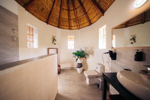 A bathroom with a thatched roof, a large sink, a toilet, and a potted plant. - Spacious Villa, 2-Min Beach Walk - AC, Wifi (Pwani Mchangani)