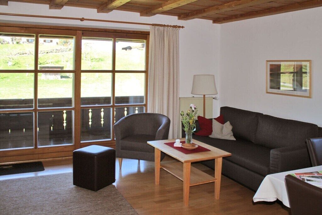 Un salon avec un canapé, un fauteuil et une table sur laquelle est posé un vase.