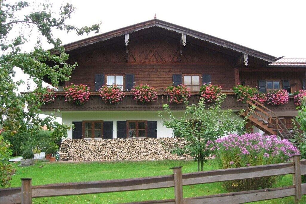 Una casa in legno tradizionale con un balcone, una scala in legno e una pila di legna da ardere.
