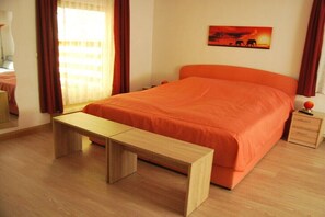 A bedroom with a bed, a wooden bench, a nightstand, and a painting on the wall.