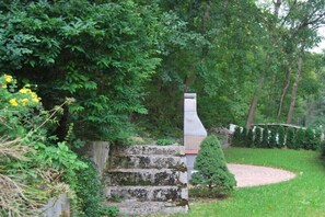 Una escala de pedra que puja a un edifici, envoltada de vegetació abundant i un jardí ben cuidat.