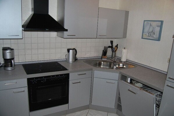 A compact kitchen with a built-in oven, a coffee maker, and a dishwasher.