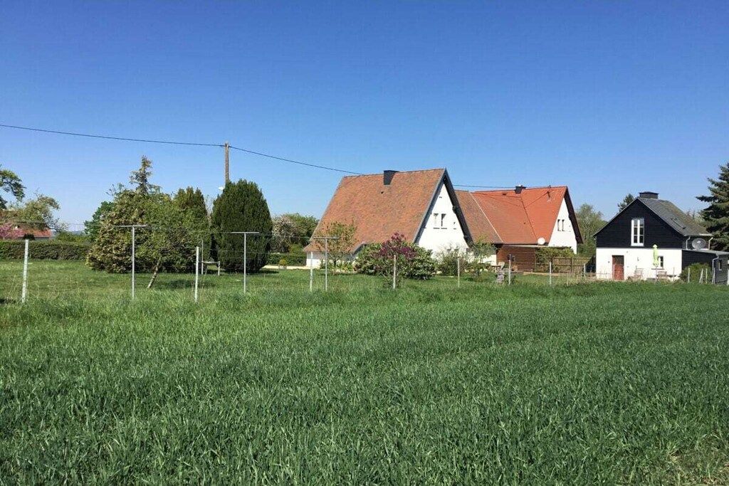 Ländliche Landschaft mit einem Feld, einem weißen Haus mit rotem Dach und einem kleineren schwarzen Haus.