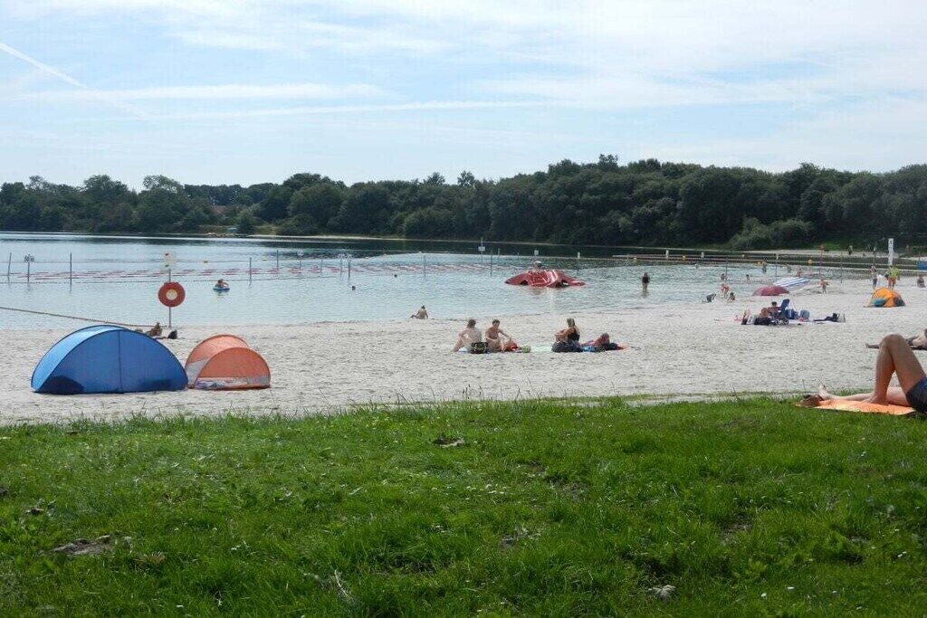 Uma praia com tendas, área para nadar e zona gramada.
