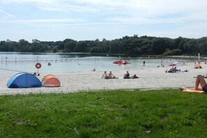 Ein Strand mit Zelten, einem Schwimmbereich und einer Rasenfläche.