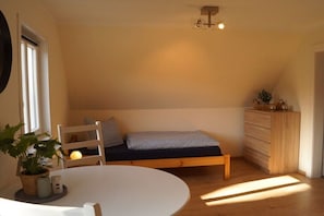 A cozy room with a bed, a dresser, a table, and a chair. - Holiday apartment with 3 bedrooms (Munster)