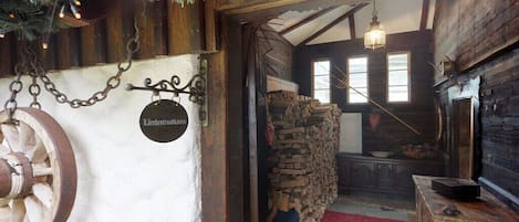A rustic interior with a wooden wheel, a stone wall, and a red carpeted floor.