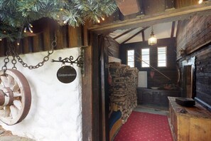 A rustic interior with a wooden wheel, a stone wall, and a red carpeted floor. - Holiday home Lärchen-Troadkastn (Patergassen)