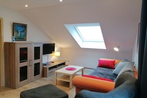 Ein kompakter Wohnraum mit Oberlicht, einer Couch, einem Tisch und einem Schrank.