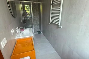Une salle de bain moderne avec une douche à parois de verre, un lavabo blanc et un porte-serviettes.