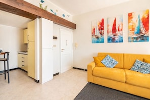 A living room with a yellow sofa, a kitchen area with yellow cabinets, and a door leading to another room. - 🏠 ACCOMMODATION DESCRIPTIONLet yourself be captivated by the timeless charm of Camogli: this apartment, directly overlooking the seaside promenade, offers an enchanting view of the sea and the beach that will stay with you from the first to the last m (Camogli)