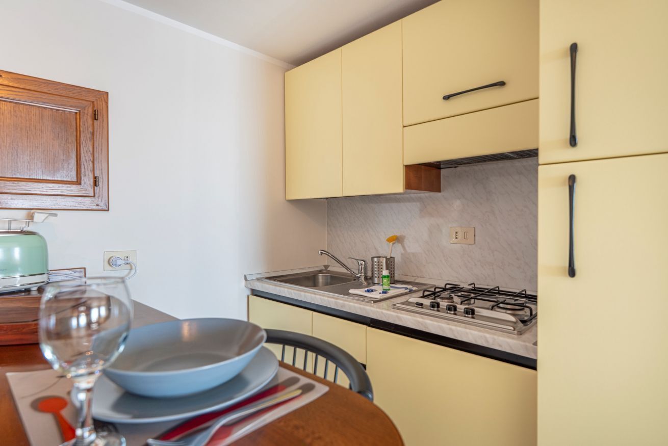 A compact kitchen with a gas stove, a sink, and a wooden cabinet.